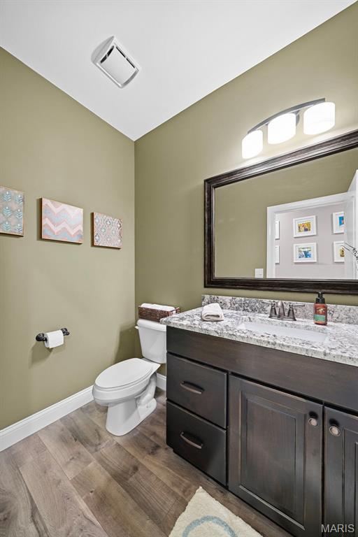 111 Foristell Ridge Ct, Foristell, MO 63348 - half bathroom with baseboards, wood finished floors, toilet, and vanity