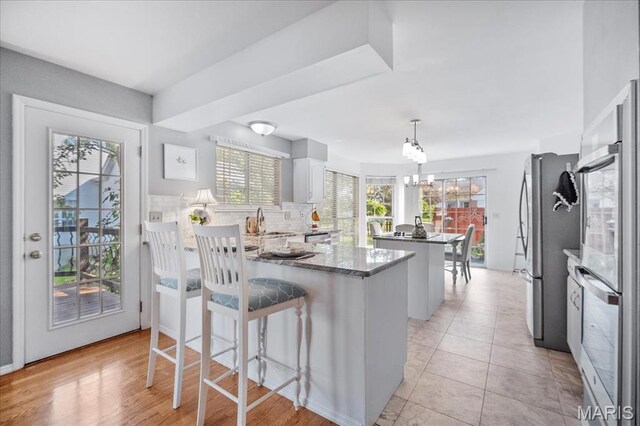 300 Wildberry Ln, Saint Charles, MO 63304 - kitchen with a center island, appliances with stainless steel finishes, a peninsula, decorative backsplash, and stone countertops