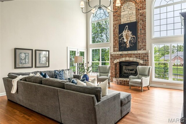 5316 Enchanted Ct, Weldon Spring, MO 63304 - living room featuring a high ceiling, a chandelier, wood finished floors, and a brick fireplace