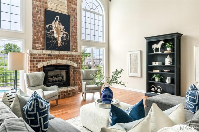 5316 Enchanted Ct, Weldon Spring, MO 63304 - living room with a high ceiling, a brick fireplace, wood finished floors, and healthy amount of natural light