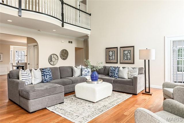 5316 Enchanted Ct, Weldon Spring, MO 63304 - living room with a towering ceiling, arched walkways, ornamental molding, light wood finished floors, and plenty of natural light