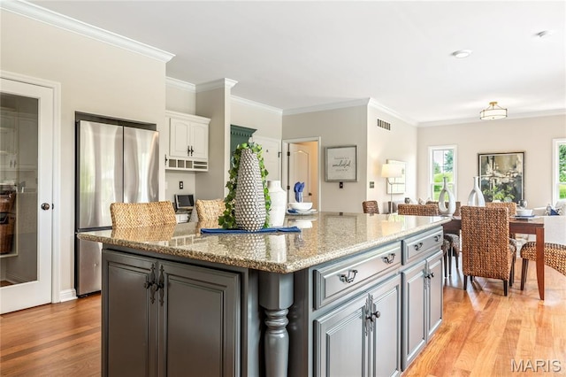 5316 Enchanted Ct, Weldon Spring, MO 63304 - kitchen featuring freestanding refrigerator, light wood-type flooring, a kitchen island, crown molding, and light stone countertops