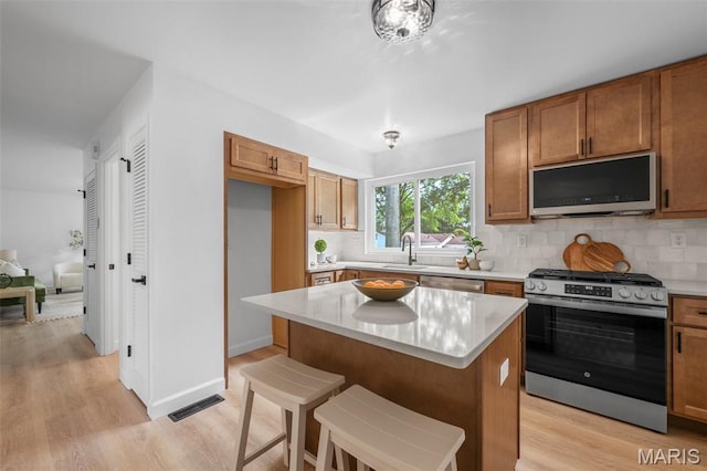 2736 Ashrock Dr, Saint Louis, MO 63129 - kitchen featuring appliances with stainless steel finishes, light wood-style flooring, and brown cabinetry