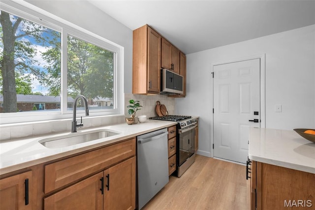 2736 Ashrock Dr, Saint Louis, MO 63129 - kitchen with appliances with stainless steel finishes, a sink, light wood-type flooring, brown cabinetry, and light countertops