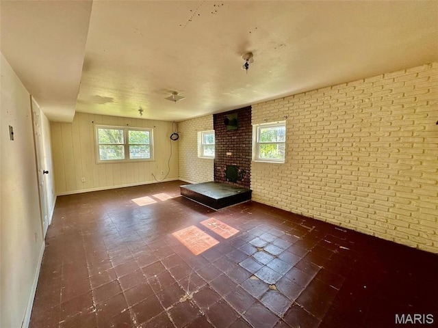 860 Chouteau Ave, Godfrey, IL 62035 - unfurnished living room featuring brick wall, baseboards, and dark floors