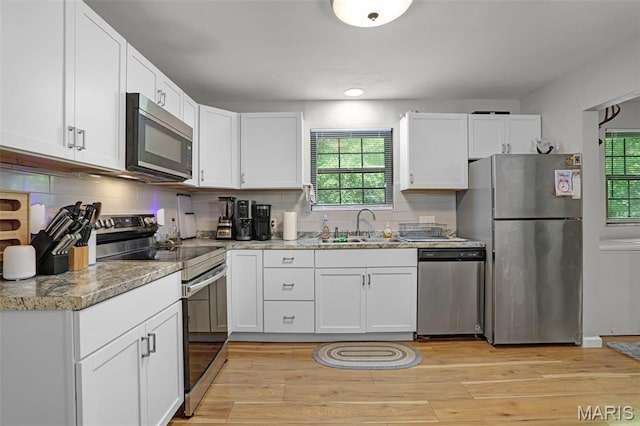 28 French Quarter, Belleville, IL 62223 - kitchen featuring stainless steel appliances, a sink, white cabinets, light wood-type flooring, and decorative backsplash
