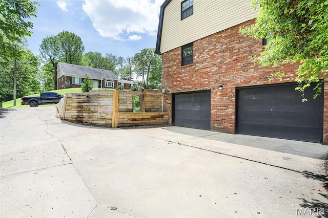28 French Quarter, Belleville, IL 62223 - view of property exterior with a garage, driveway, brick siding, and fence