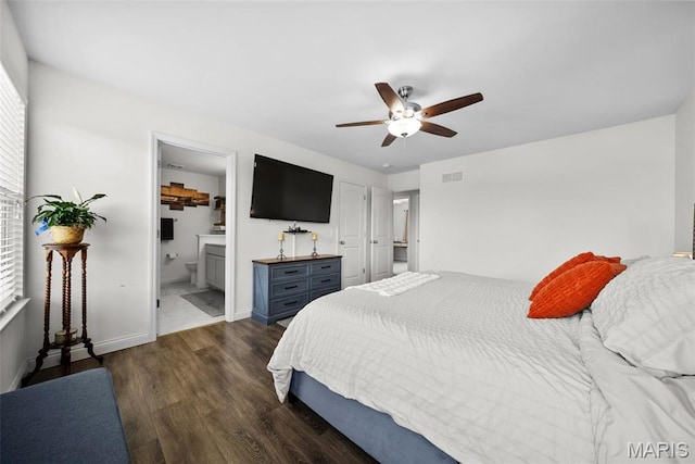 bedroom featuring wood finished floors, baseboards, ensuite bathroom, and ceiling fan