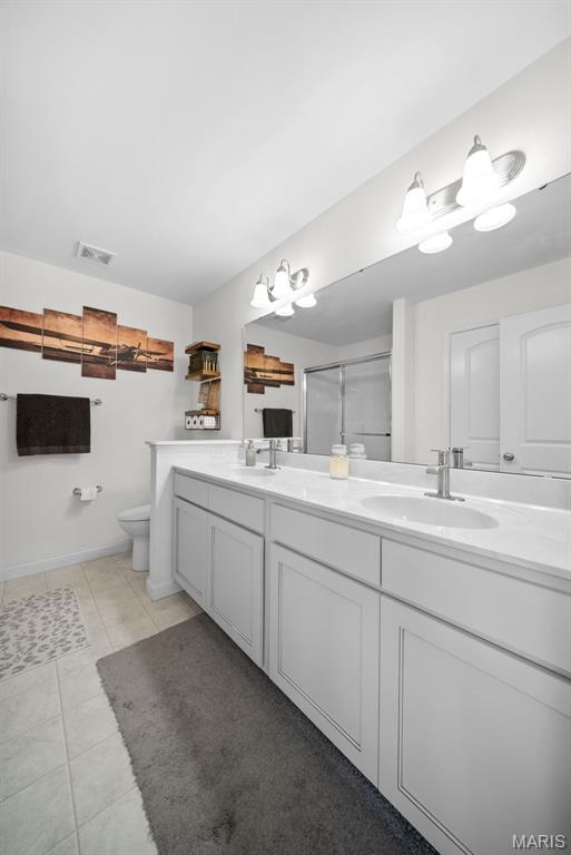 full bathroom with toilet, double vanity, a shower with door, tile patterned floors, and baseboards