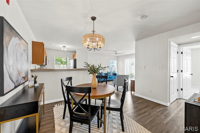 dining area with dark wood-style floors, a chandelier, baseboards, and ceiling fan