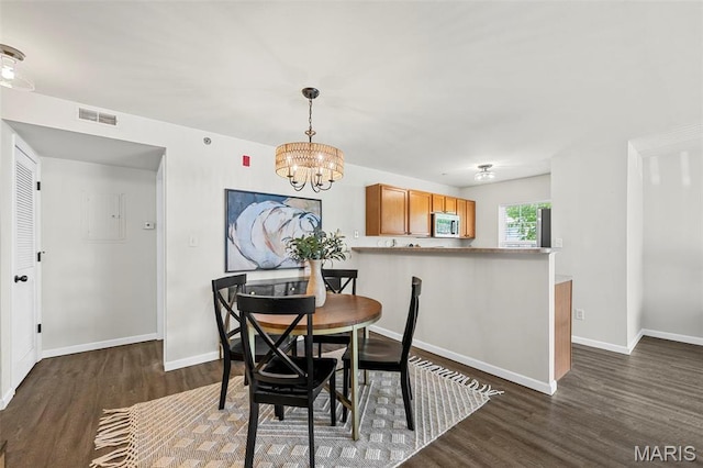 dining area featuring dark wood-type flooring, a chandelier, and baseboards