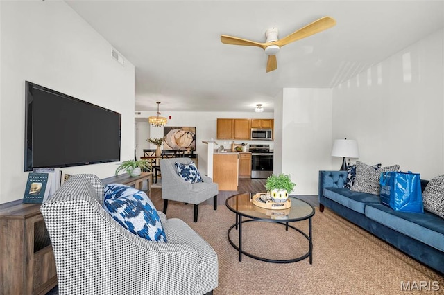 carpeted living area featuring a ceiling fan and a chandelier