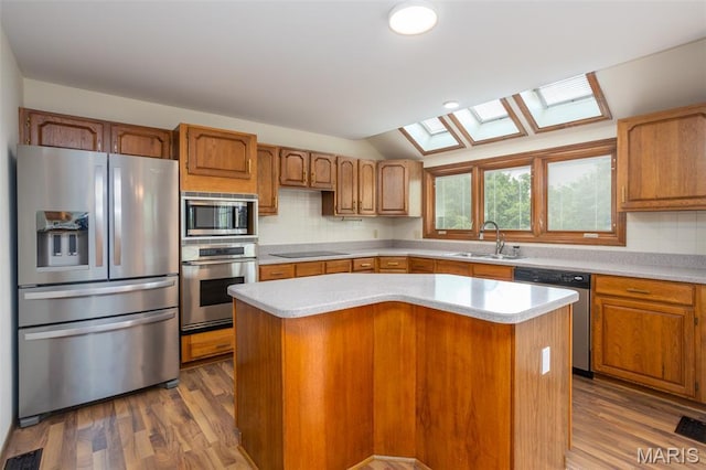712 Carman Oaks Ct, Manchester, MO 63021 - kitchen with appliances with stainless steel finishes, a sink, light countertops, a skylight, and a center island