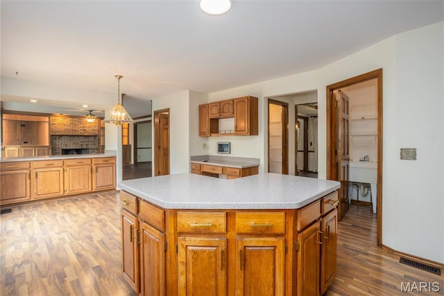 712 Carman Oaks Ct, Manchester, MO 63021 - kitchen with wood finished floors, a kitchen island, light countertops, brown cabinetry, and baseboards
