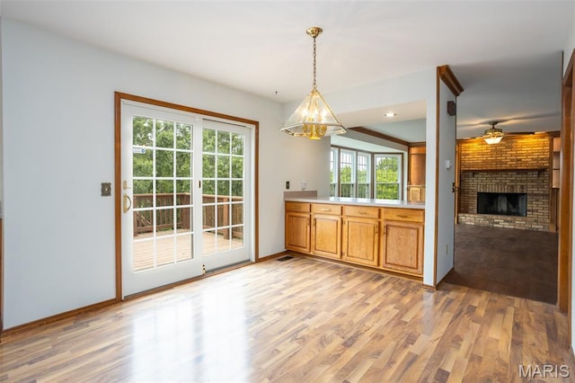 712 Carman Oaks Ct, Manchester, MO 63021 - kitchen with light wood-style flooring, a chandelier, a fireplace, light countertops, and pendant lighting