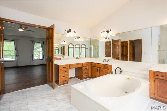 712 Carman Oaks Ct, Manchester, MO 63021 - bathroom featuring vaulted ceiling, marble look tiles, a garden tub, a ceiling fan, and vanity