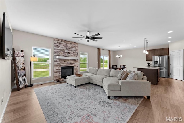 living area featuring light wood-style floors, a ceiling fan, recessed lighting, baseboards, and a chandelier