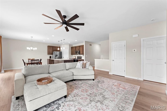 living area featuring ceiling fan, light wood finished floors, baseboards, a chandelier, and recessed lighting