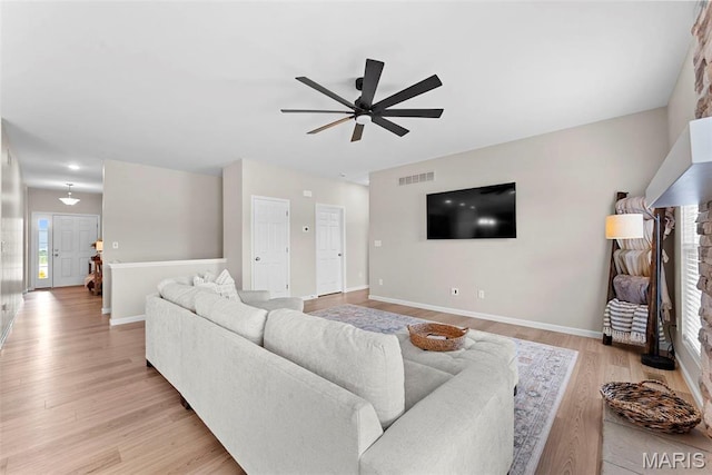 living area with a ceiling fan, light wood finished floors, and baseboards