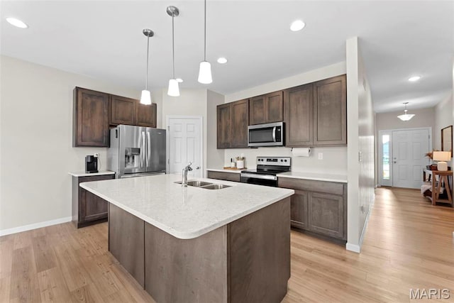 kitchen featuring stainless steel appliances, a sink, dark brown cabinets, light wood-style floors, and baseboards