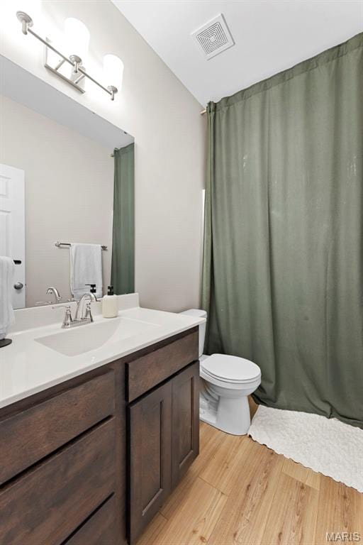 bathroom featuring wood finished floors, toilet, and vanity