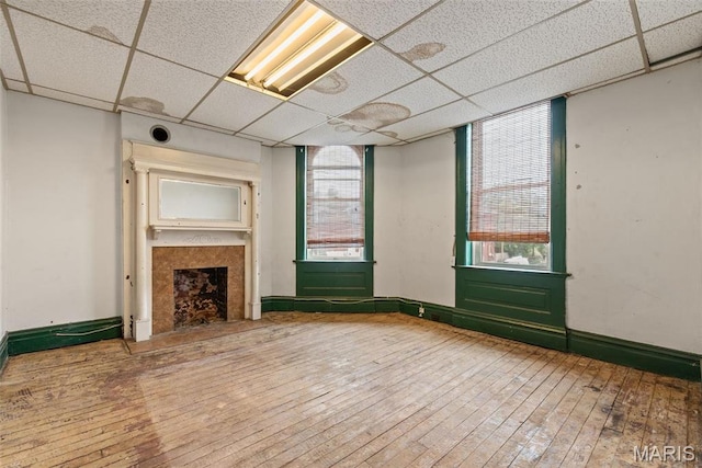 3456 Miami St, Saint Louis, MO 63118 - unfurnished living room with a drop ceiling, wood-type flooring, a fireplace, and baseboards