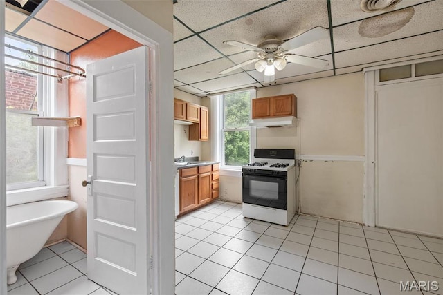 3456 Miami St, Saint Louis, MO 63118 - kitchen featuring range with gas cooktop, under cabinet range hood, light tile patterned floors, ceiling fan, and a sink