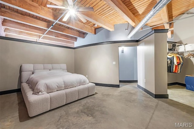 bedroom with concrete floors, wooden ceiling, baseboards, beam ceiling, and a walk in closet