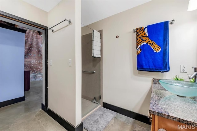 bathroom with finished concrete flooring, a shower stall, vanity, and baseboards