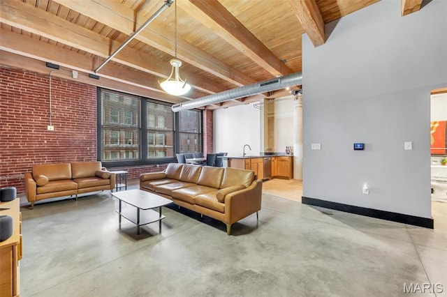 living area with wooden ceiling, concrete floors, beamed ceiling, brick wall, and baseboards