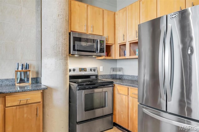 kitchen with appliances with stainless steel finishes, dark stone countertops, and open shelves