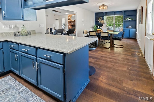 kitchen featuring blue cabinetry, a peninsula, ceiling fan, and dark wood-type flooring
