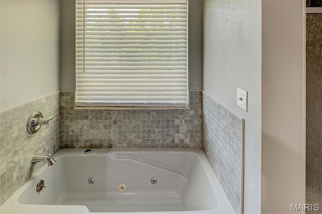 full bathroom featuring a jetted tub, plenty of natural light, and a wainscoted wall