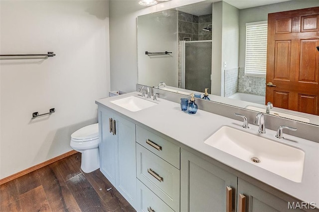 full bath featuring a shower stall, wood finished floors, toilet, baseboards, and double vanity