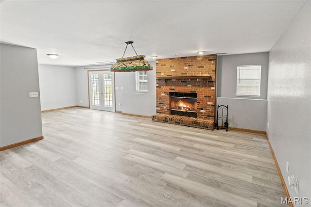 unfurnished living room with baseboards, wood finished floors, and a fireplace