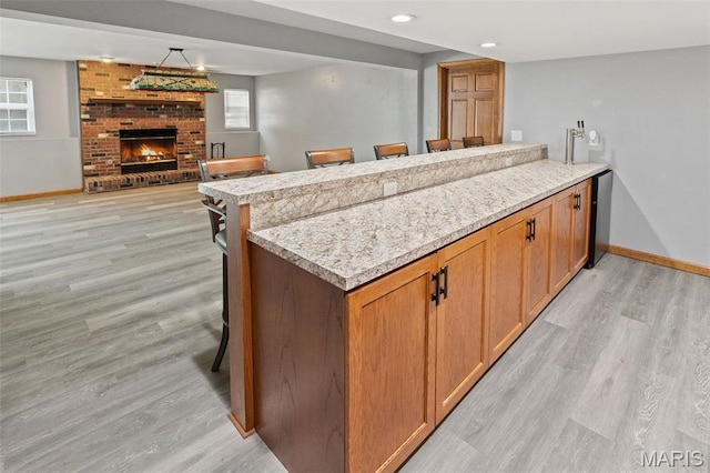 kitchen featuring baseboards, light wood-style flooring, a peninsula, and recessed lighting