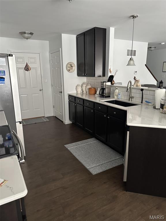 1805 Hyland Green Dr, Ofallon, MO 63366 - kitchen with a peninsula, freestanding refrigerator, a sink, dark cabinets, and dark wood finished floors