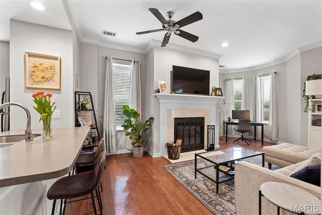 4260 Lindell Blvd Unit B, Saint Louis, MO 63108 - living area featuring wood finished floors, a tiled fireplace, a ceiling fan, crown molding, and baseboards