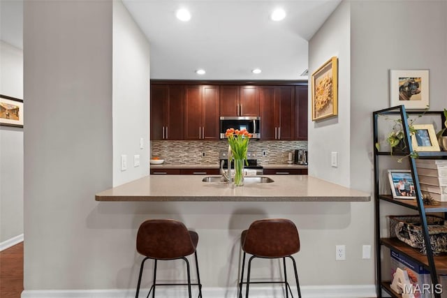 4260 Lindell Blvd Unit B, Saint Louis, MO 63108 - kitchen with appliances with stainless steel finishes, a kitchen breakfast bar, decorative backsplash, baseboards, and a sink