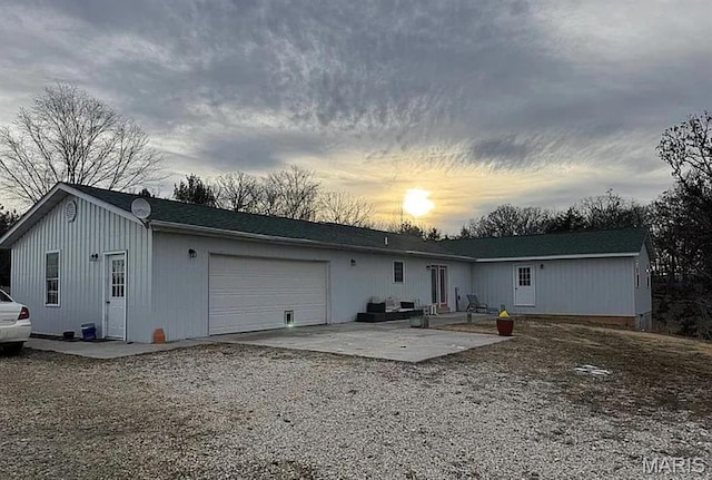23784 Maries Road 410th Rd, Belle, MO 65013 - back of property at dusk with a garage, gravel driveway, and a patio