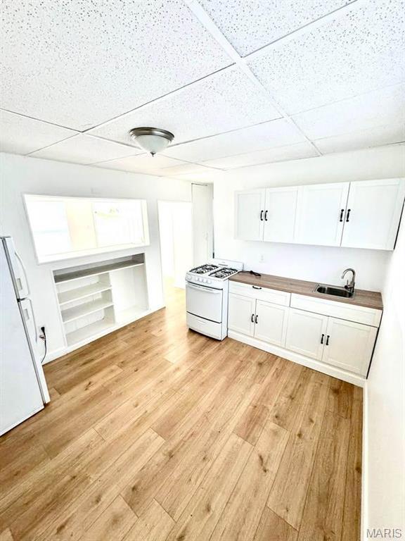 10117 Duke Dr, Saint Louis, MO 63136 - kitchen with white appliances, a sink, light wood-style floors, white cabinetry, and a paneled ceiling