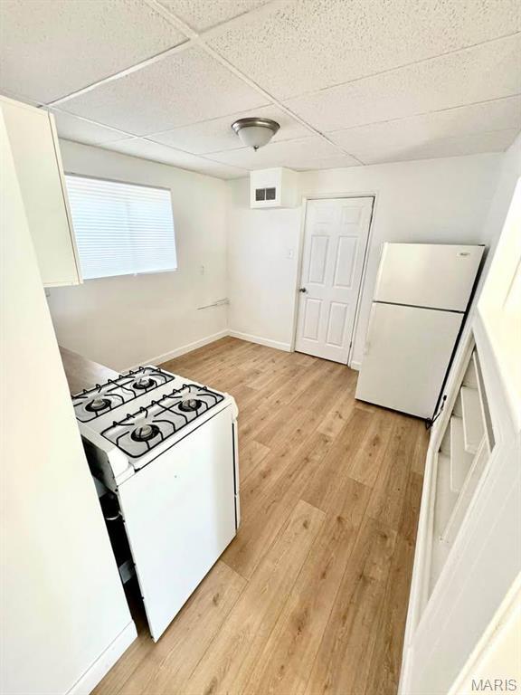 10117 Duke Dr, Saint Louis, MO 63136 - kitchen featuring gas range oven, freestanding refrigerator, a drop ceiling, light wood-style floors, and baseboards