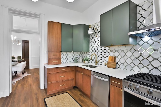 6504 Michigan Ave, Saint Louis, MO 63111 - kitchen featuring appliances with stainless steel finishes, wall chimney range hood, a sink, light countertops, and dark wood-style flooring