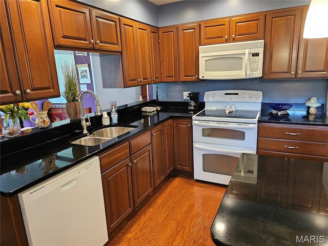 1117 Meadow Ln, Sparta, IL 62286 - kitchen with white appliances, a sink, light wood-style flooring, brown cabinets, and dark stone countertops