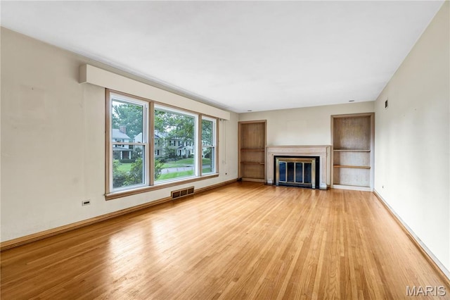 369 Halcyon Dr, Saint Louis, MO 63122 - unfurnished living room featuring light wood-type flooring and a glass covered fireplace