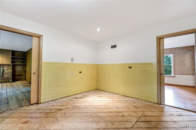 369 Halcyon Dr, Saint Louis, MO 63122 - unfurnished room featuring wood-type flooring, a wainscoted wall, tile walls, and a fireplace