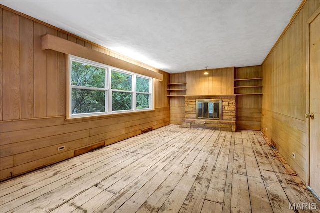 369 Halcyon Dr, Saint Louis, MO 63122 - unfurnished living room with wood walls, a stone fireplace, built in shelves, and hardwood / wood-style floors