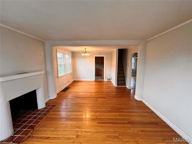 6604 Donald St, Saint Louis, MO 63121 - unfurnished living room with light wood finished floors, a tiled fireplace, a chandelier, stairs, and arched walkways