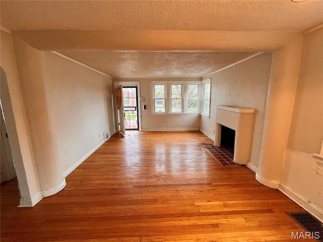 6604 Donald St, Saint Louis, MO 63121 - unfurnished living room featuring a textured ceiling, hardwood / wood-style flooring, a fireplace, and ornamental molding