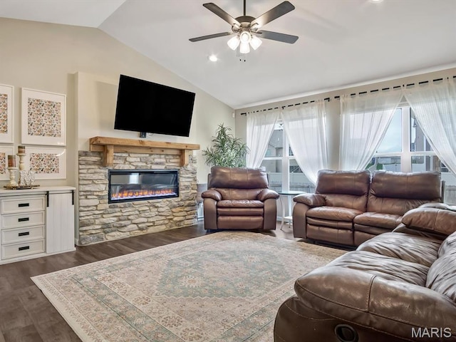living area featuring lofted ceiling, a ceiling fan, dark wood finished floors, and a stone fireplace